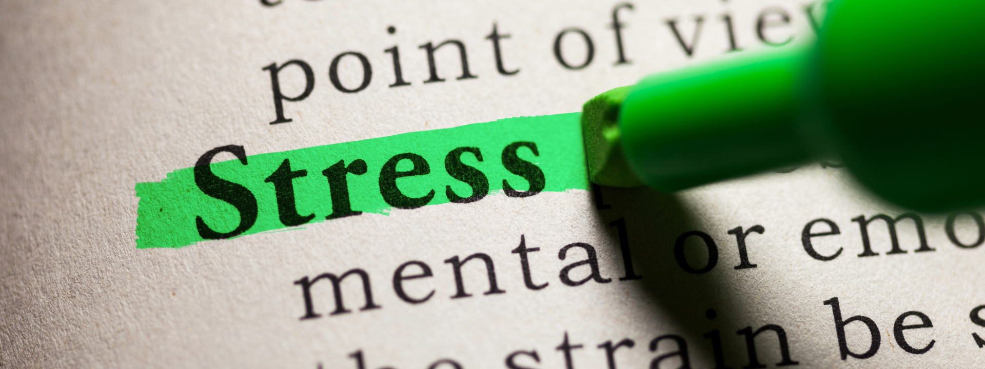 The word stress highlighted in green marker on a dictionary page, close-up view.